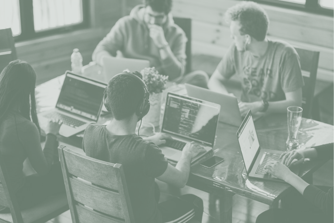 Group Sat At Table On Computers